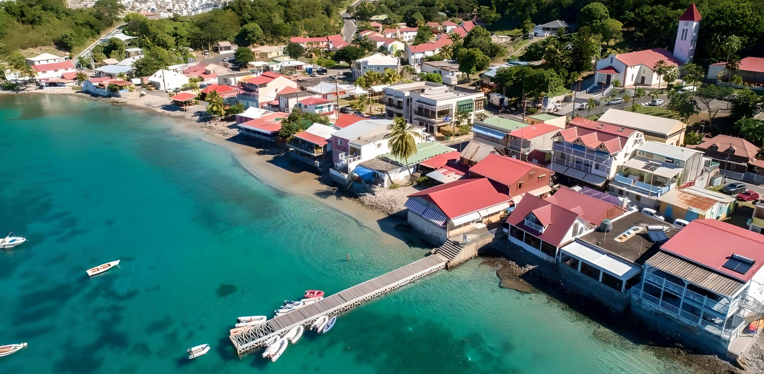 Vue aérienne du bourg de Deshaies en Guadeloupe, entre mer turquoise et toits colorés
