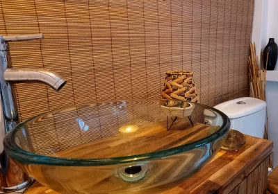 vasque transparente verre sur table bois et wc devant store bambou hébergement coco carib, Deshaies Guadeloupe