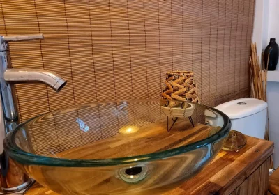 vasque transparente verre sur table bois et wc devant store bambou hébergement coco carib, Deshaies Guadeloupe